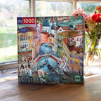 Jigsaw puzzle box with a colorful illustration of a city scene on a wooden surface. Artists in Venice Italy 1000 Piece Puzzle