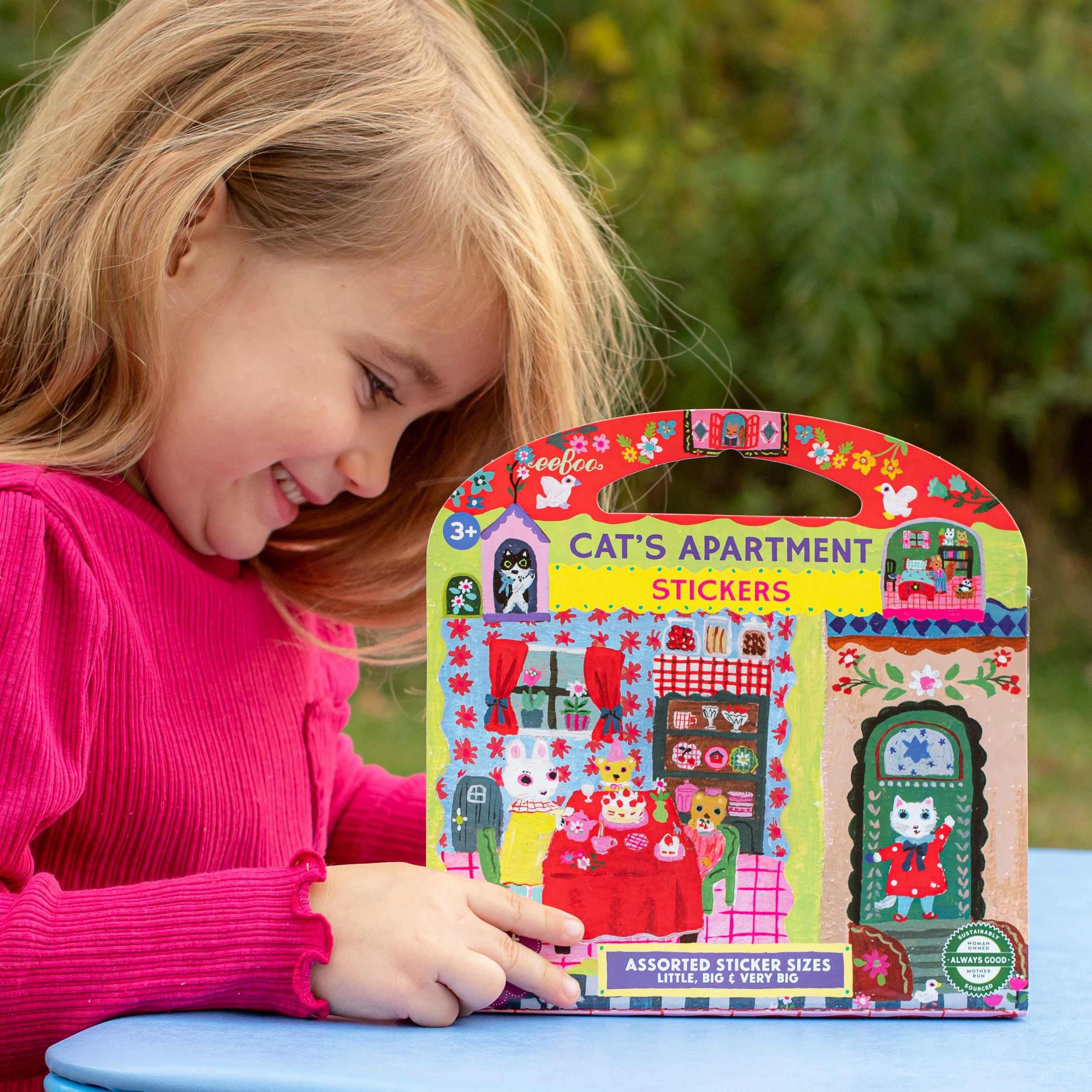 Child holding a 'Cat's Apartment' stickers pack with a colorful design